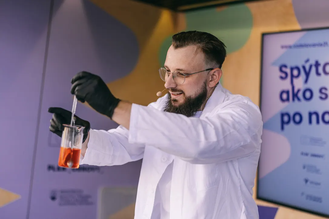 Chemik ukazuje prácu s pipetou a skúmavkou
