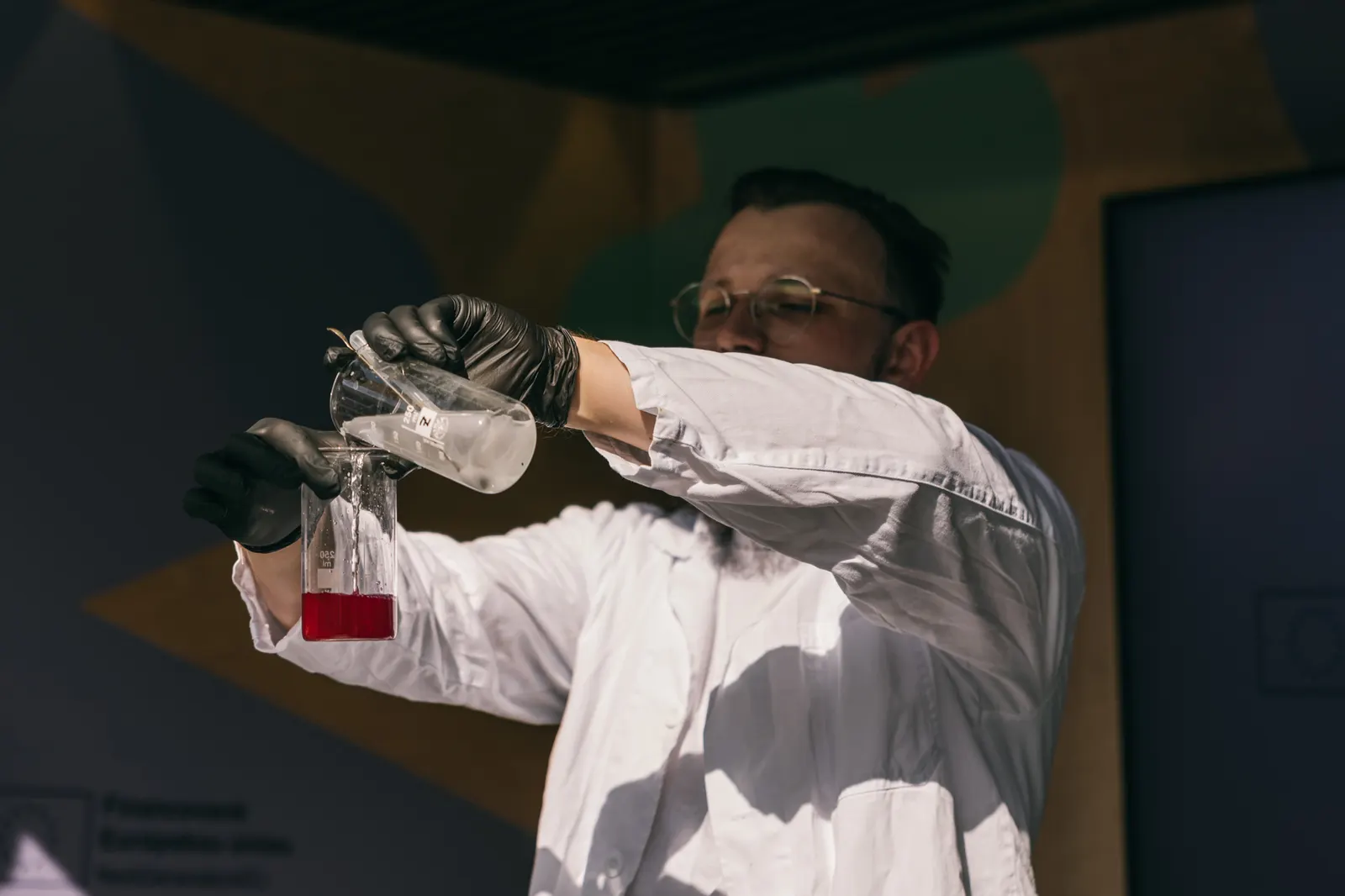 Chemik prelieva farebnú tekutinu medzi kadičkami